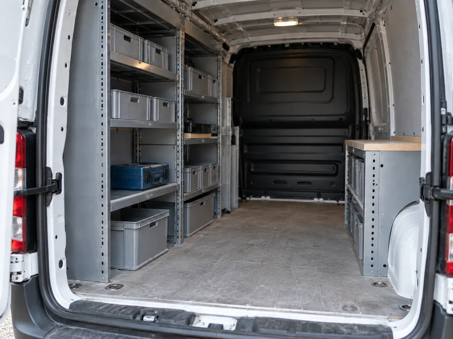 Empty van interior with shelving and plain grey bins.